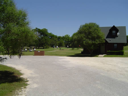 A photo of the cabin area with some people playing golf in the background.